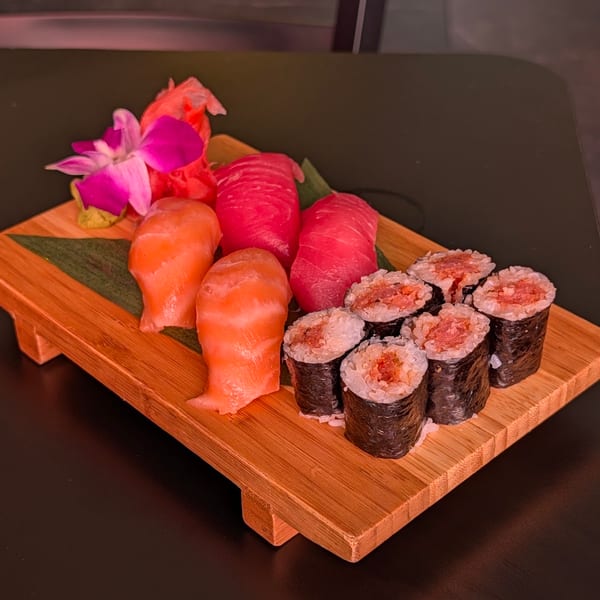 Sushi platter with salmon and tuna nigiri, maki rolls, ginger, wasabi, and an orchid.